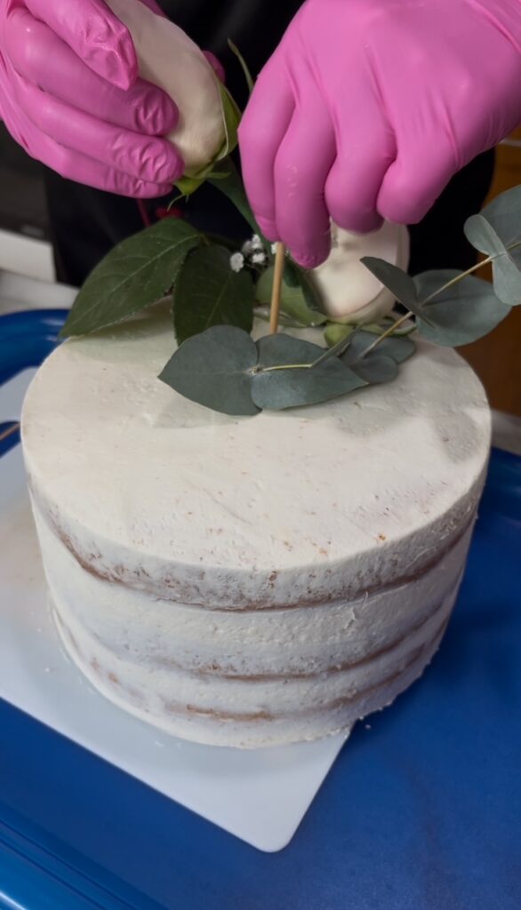 Los pasteles decorados con flores naturales requieren precisión en su decoración, así como se observa en la imagen, las flores se colocn con cuidado.