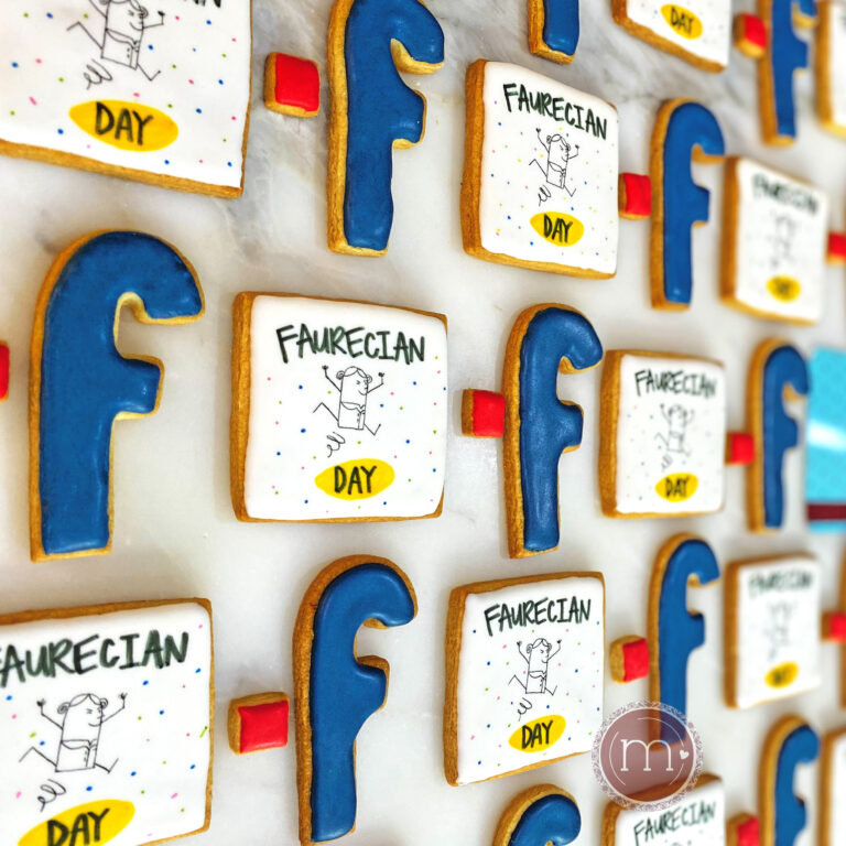 Un grupo de galletas acomodadas en filas. Unas galletas tienen forma de la letra "f" y son decoradas con glaseado azul y otras tienen forma cuadrada. Estas galletas personalizadas para la empresa "Faurecian" tienen un diseño del logo de la empresa y se colocan sobre una base blanca.