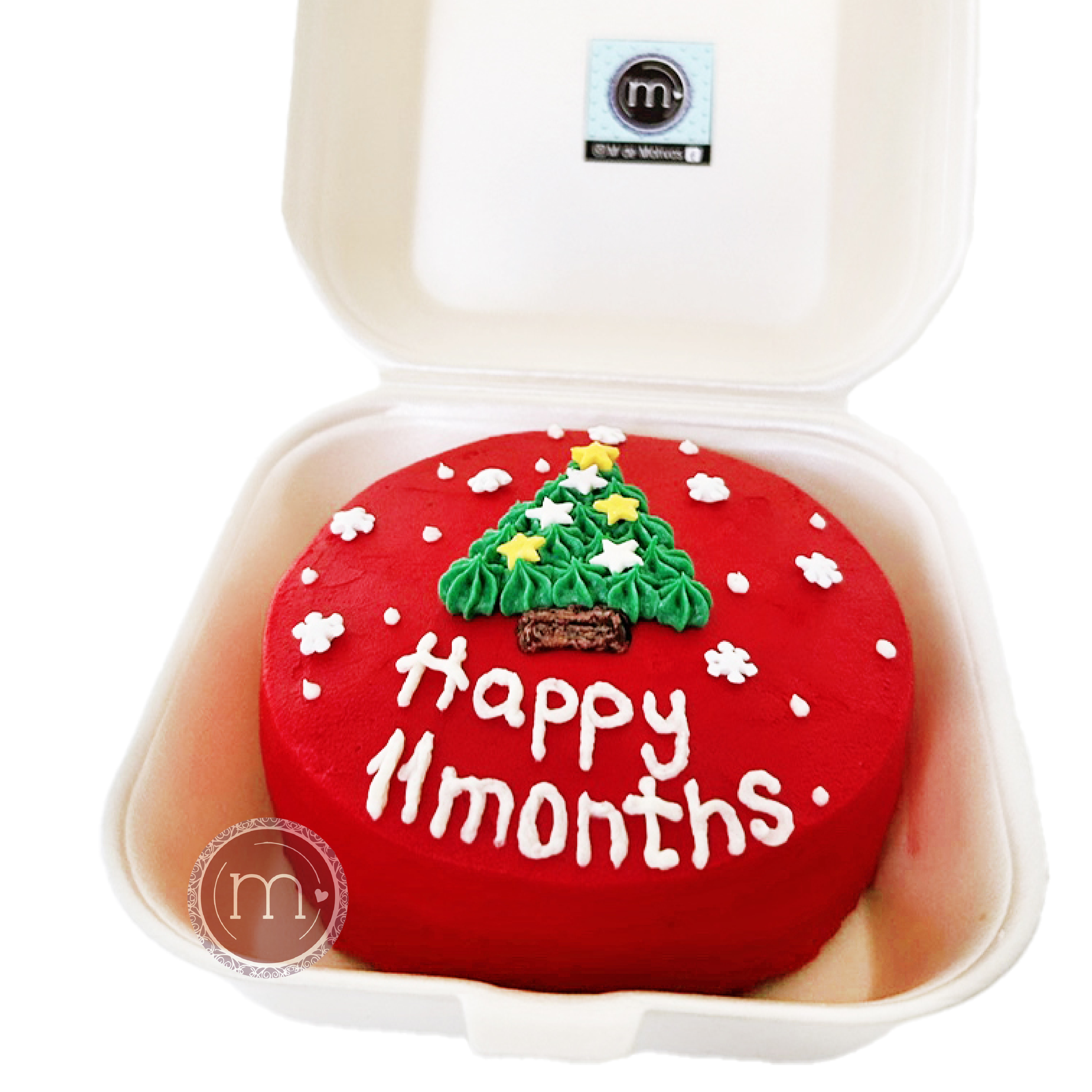 Un mini pastel personalizado con un tema navideño y la frase "happy 11 months". El pastel es de color rojo y tiene un dibujo de pino verde en la parte superior.
