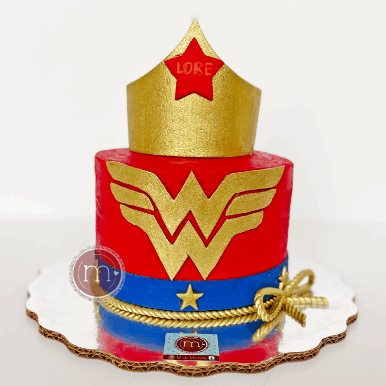 Un pastel color rojo con azul marino y dorado que en la parte frontal tiene el logo de la "Wonderwoman". En la parte superior se coloca una corona dorada hecha con fondant. Los pasteles fondant para fiestas infantiles son muy visuales. El pastel se coloca sobre una base reflectante.