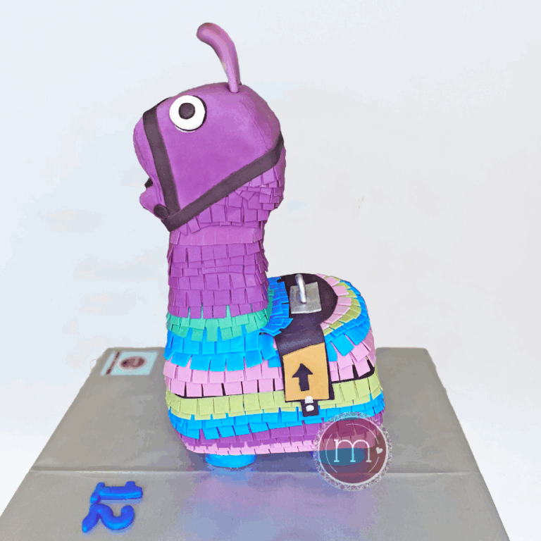 Un pastel en forma de piñata decorado con fondant de colores. Los pasteles fondant personalizados son ideales para los cumpleaños. El pastel se coloca sobre una base plateada reflectante de forma rectangular.