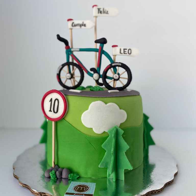 Pasteles personalizados de cumpleaños como este, tienen detalles que expresan la personalidad de la persona festejada. Este pastel tiene una decoración de fondant que simula un paisaje montañoso y en la parte superior se coloca una bicleta de fondant con unos banderines que dicen "feliz cumple". El papel se coloca sobre una base reflectante..