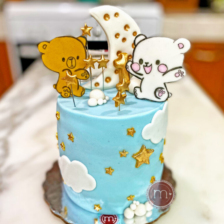 Un pastel de color azul decorado con estrellas doradas y nubes. En la parte superior se colocan dos osos, uno de color café y uno de color blanco,Detrás de los osos se coloca una luna con detalles dorados. Las decoraciones de este tipo de pasteles personalizados suelen ser de fondant pues son más detalladas.