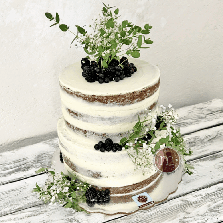 Un pastel de bodas estilo rústico. El pastel está decorado con flores y frutos del bsoque. El pastel se coloca sobre una base de madera. Pastl hecho por m de motivos respotería personalizada en Puebla.