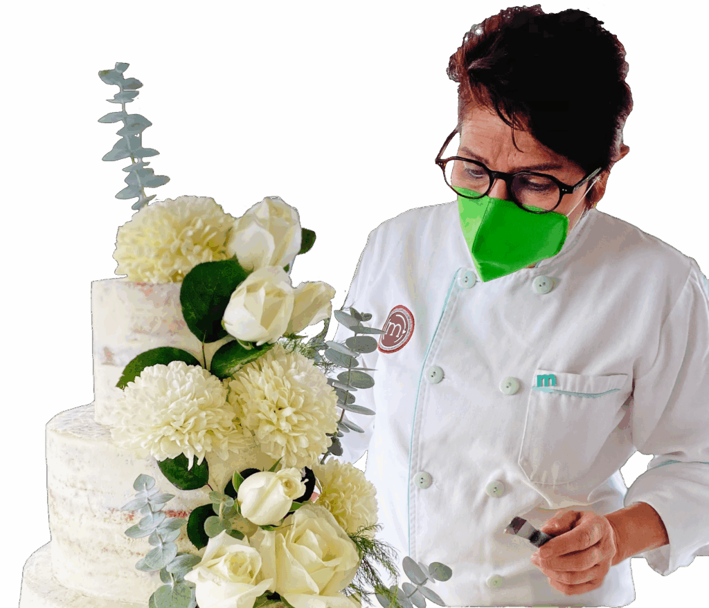 Repostera Margarita Marín, decorando un pastel de bodas. Los pasteles de bodas son parte de los servicios de repostería personalizada Puebla que ofrece "m de motivos".