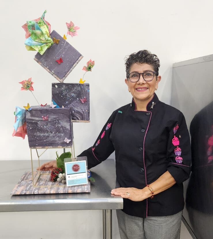 Margarita Marin de m de motivos, repostería personalizada en puebla, posa junto a un pastel de fondant en expobodas.
