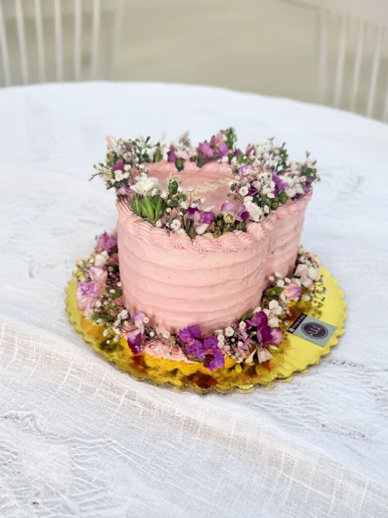 Un pastel con forma de forma con una acabado en relieves y decorado con flores en la parte sperior y en la base.Los mini pasteles con flores son tendencia en repostería