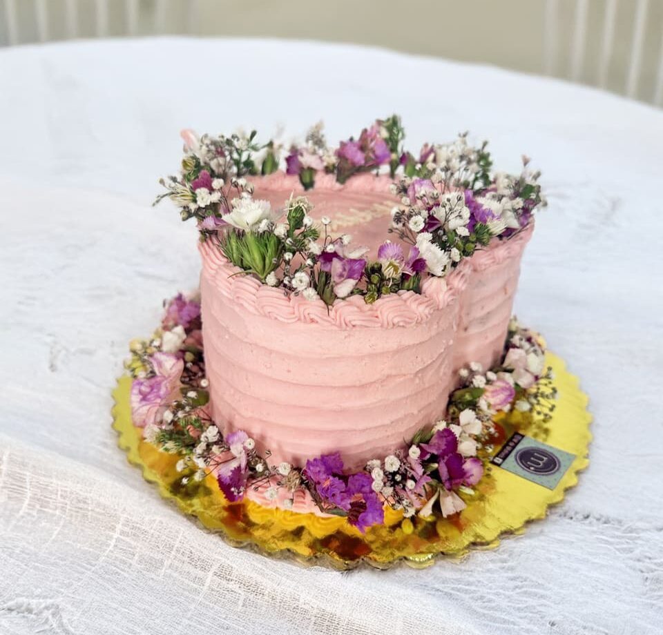 Un pastel con forma de forma con una acabado en relieves y decorado con flores en la parte sperior y en la base.Los mini pasteles con flores son tendencia en repostería
