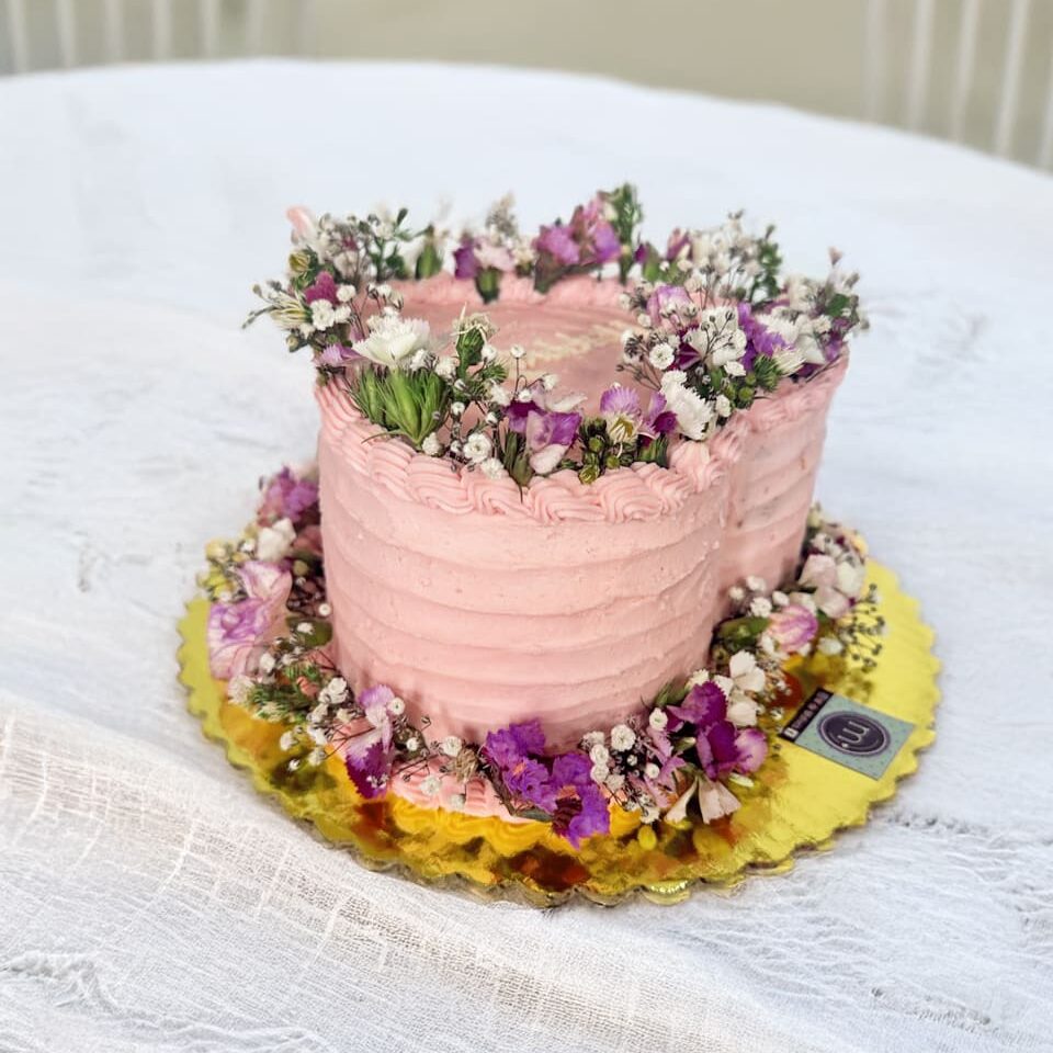 Un pastel con forma de forma con una acabado en relieves y decorado con flores en la parte sperior y en la base.Los mini pasteles con flores son tendencia en repostería