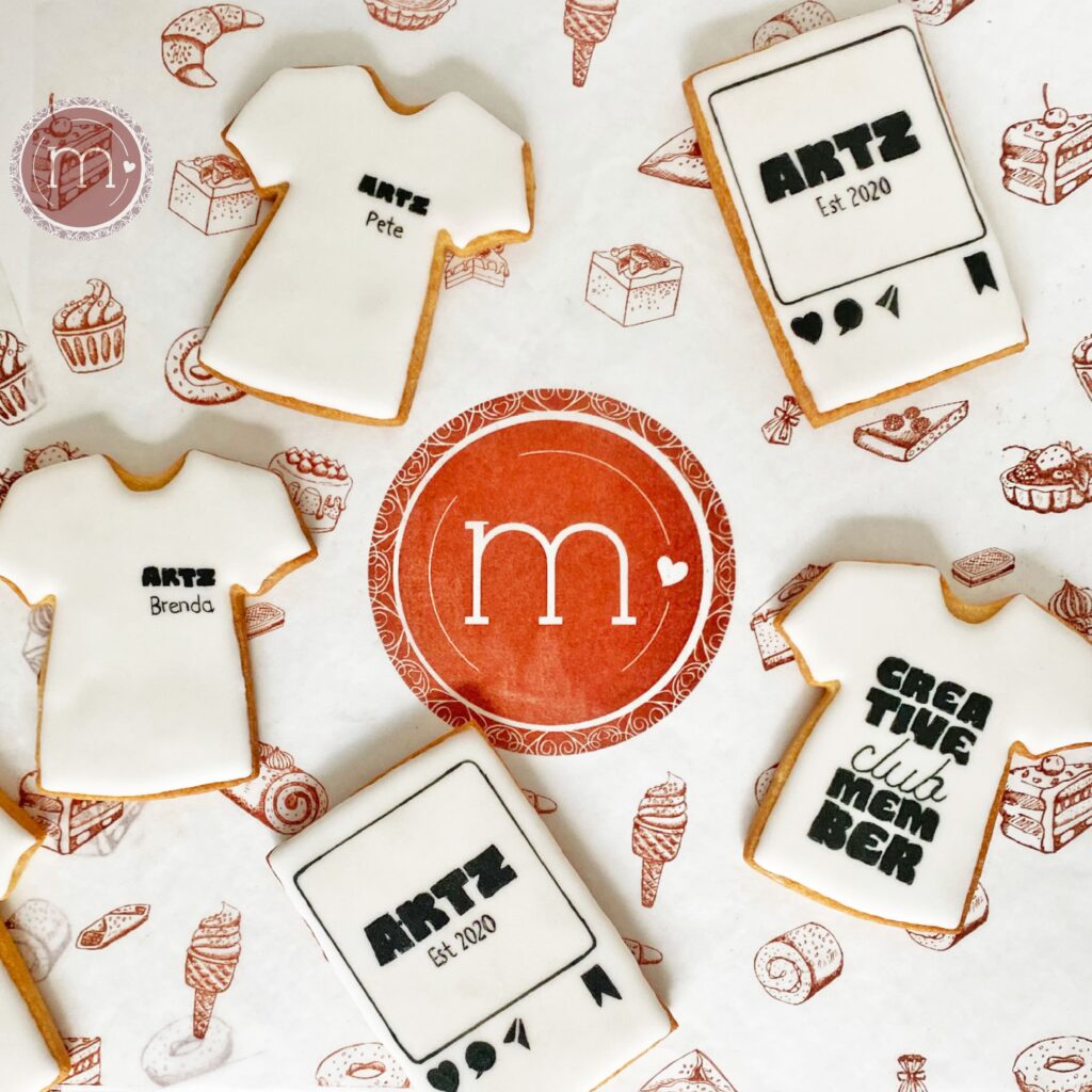 Galletas personalizadas para regalos para clientes de empresa. Se colocan 5 galletas, 3 en forma de playera con nombres y otras en forma de tarjeta con el nombre de la empresa. En Puebla m de motivos realiza galletas personalizadas.