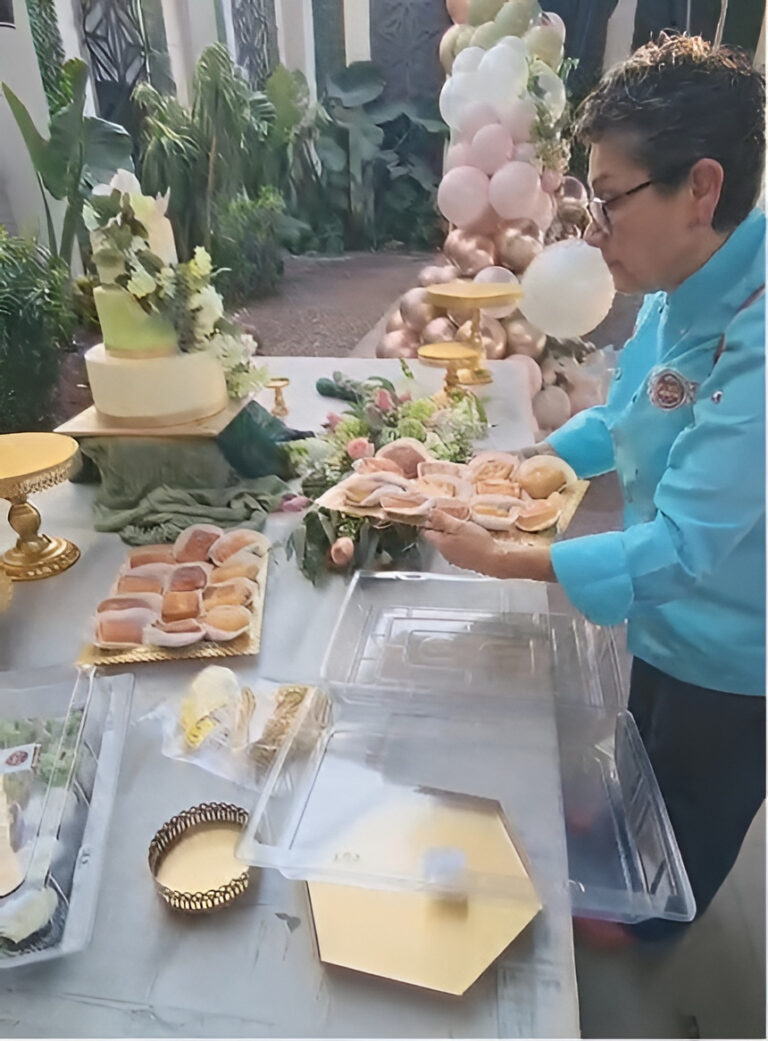 M de motivos, pasteles personalizados Puebla hace mesas de postres para fiestas. En la imagen se ve a una mujer colocando postres en una mesa de postres temática de La Princesa y El Sapo.