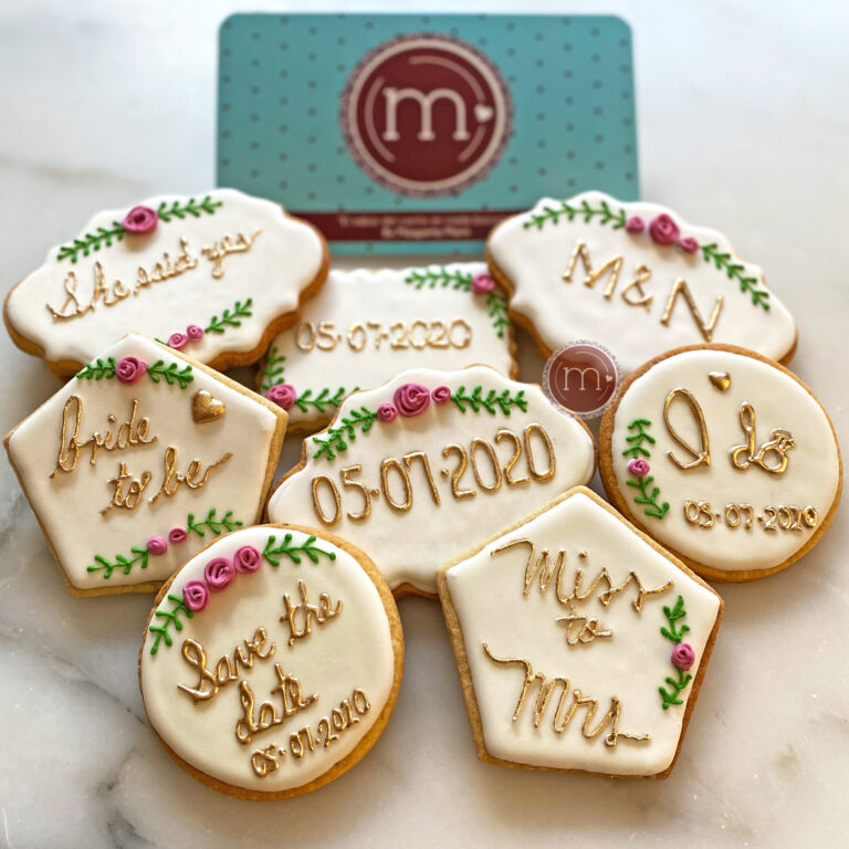 Un grupo de galletas personalizadas para bodas en Puebla. Cada galleta tiene un diseño de frases y fechas de la boda. En una galleta se lee "Miss and Mrs." en otr galleta dice la fecha "05072020".Las galletas se colocan sobre una base blanco.