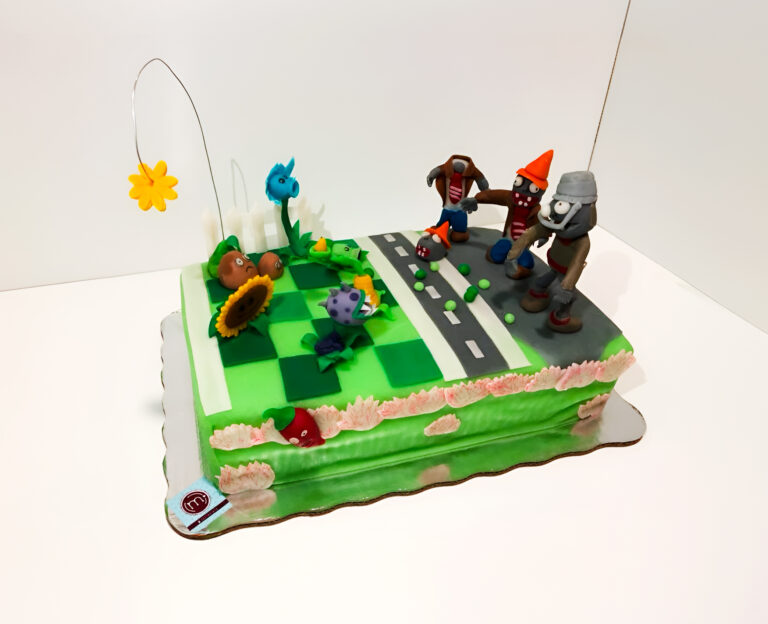 Pasteles personalizados para cumpleaños de niño.Pasteles fondant de Plant vs Zombies. Pastel decorado con fondant con zombies y personajes del videojuego. El pastel se coloca sobre una base reflectante dentro de un espacio blanco.
