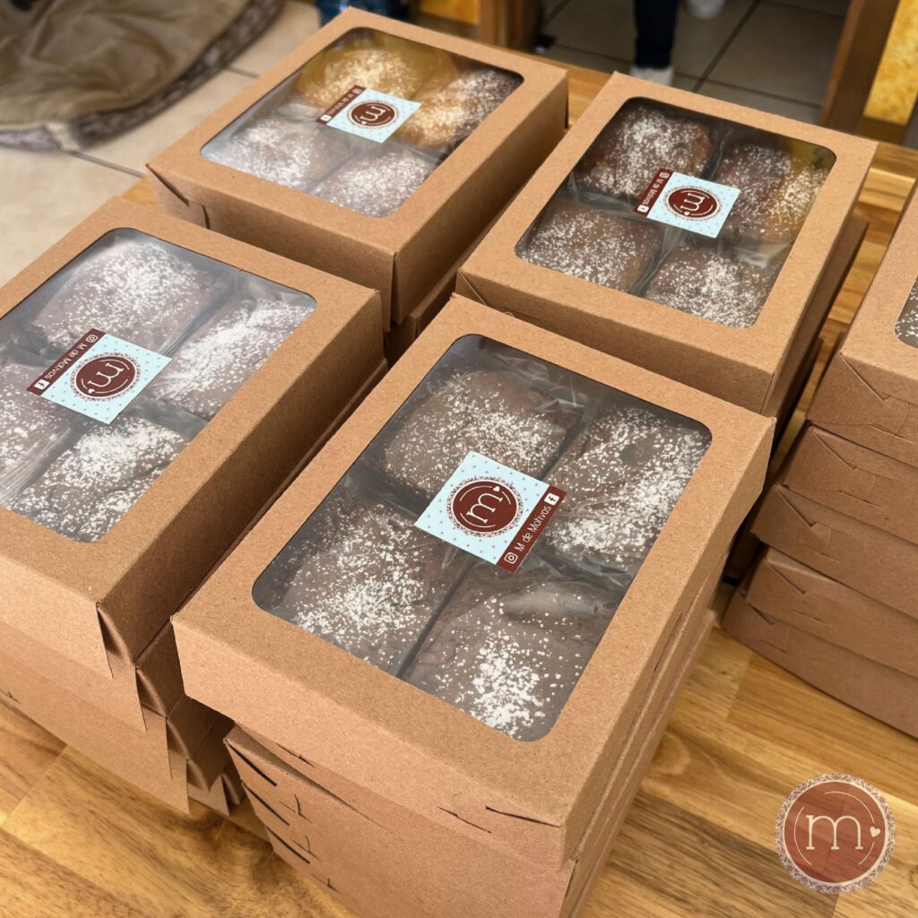Cajas con 4 piezas de brownies personalizadas para regalos para clientes en Puebla. Sobre las cajas se coloca el logo d ela repostería m de motivos.