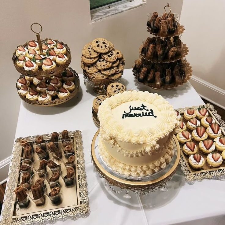 Una mesa de postres para bodas en Puebla compuesta por un pastel que dice "Just Married", galletas, cupcakes y pequeñas trufas a los costados. Los postres se colocan sobre una mesa cuadrada.